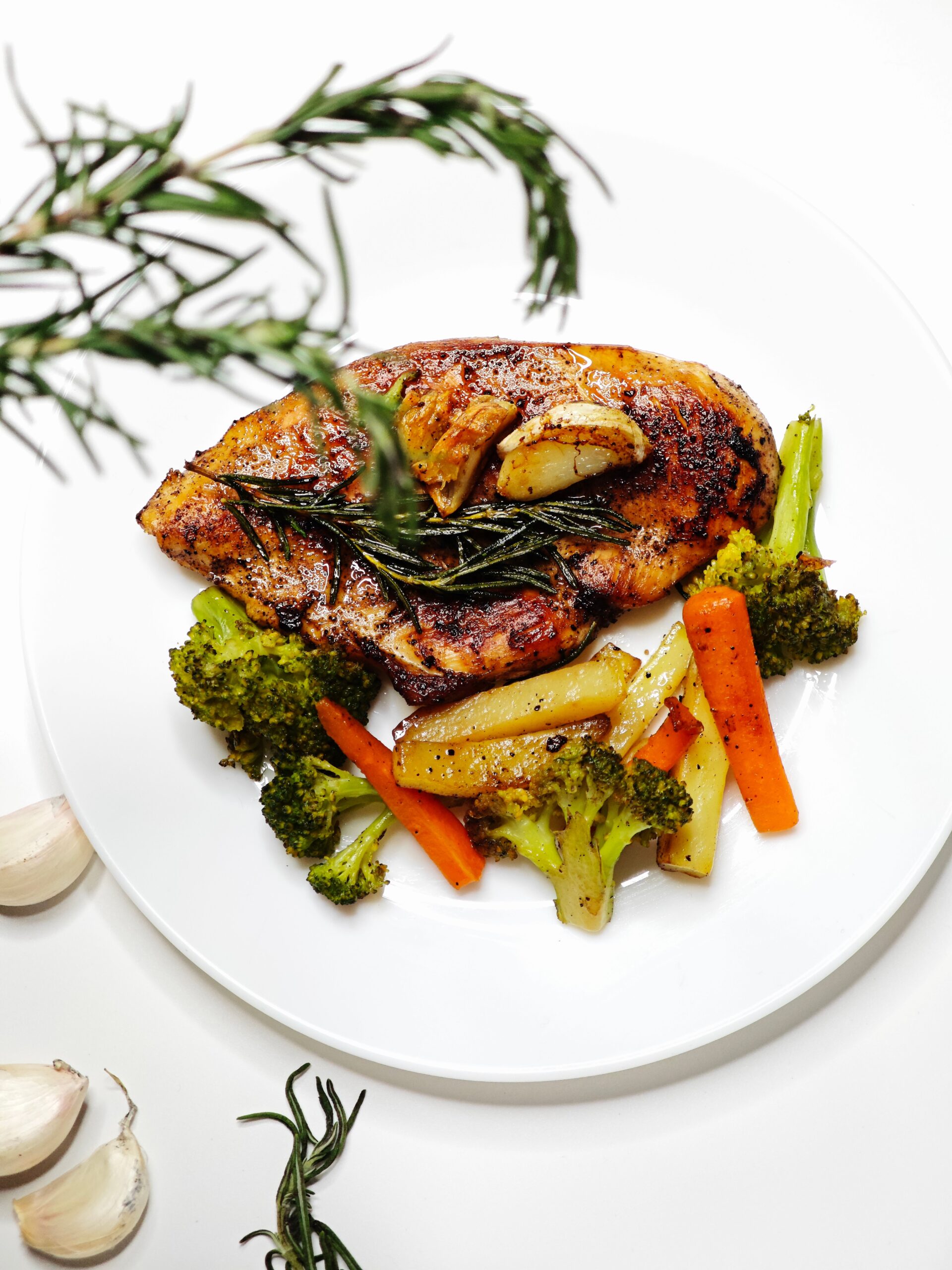 Golden brown garlic butter chicken bites plated with roasted vegetables and rosemary