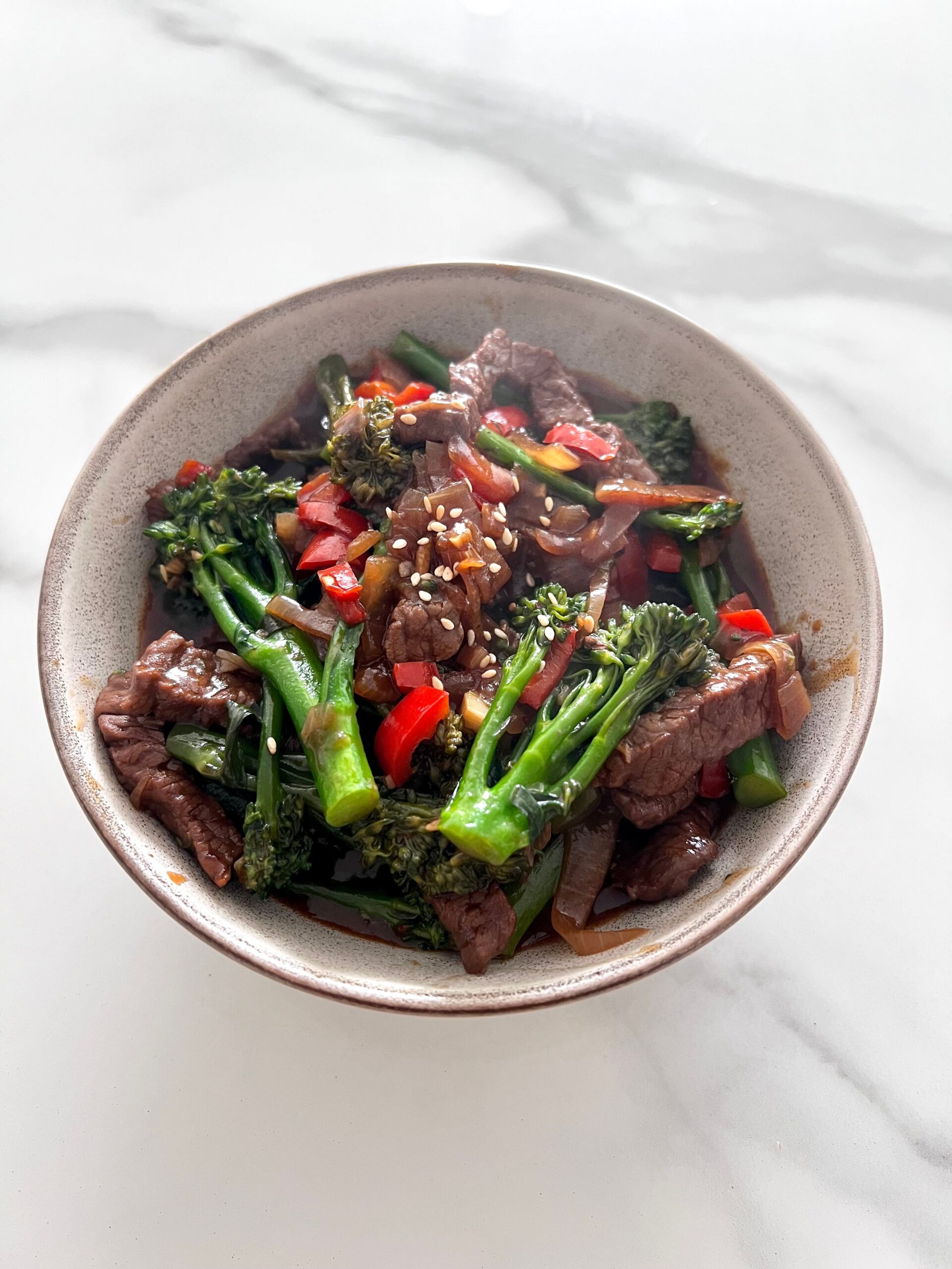 Savory beef strips and tender broccoli stir-fry simmering with red peppers in garlic sauce