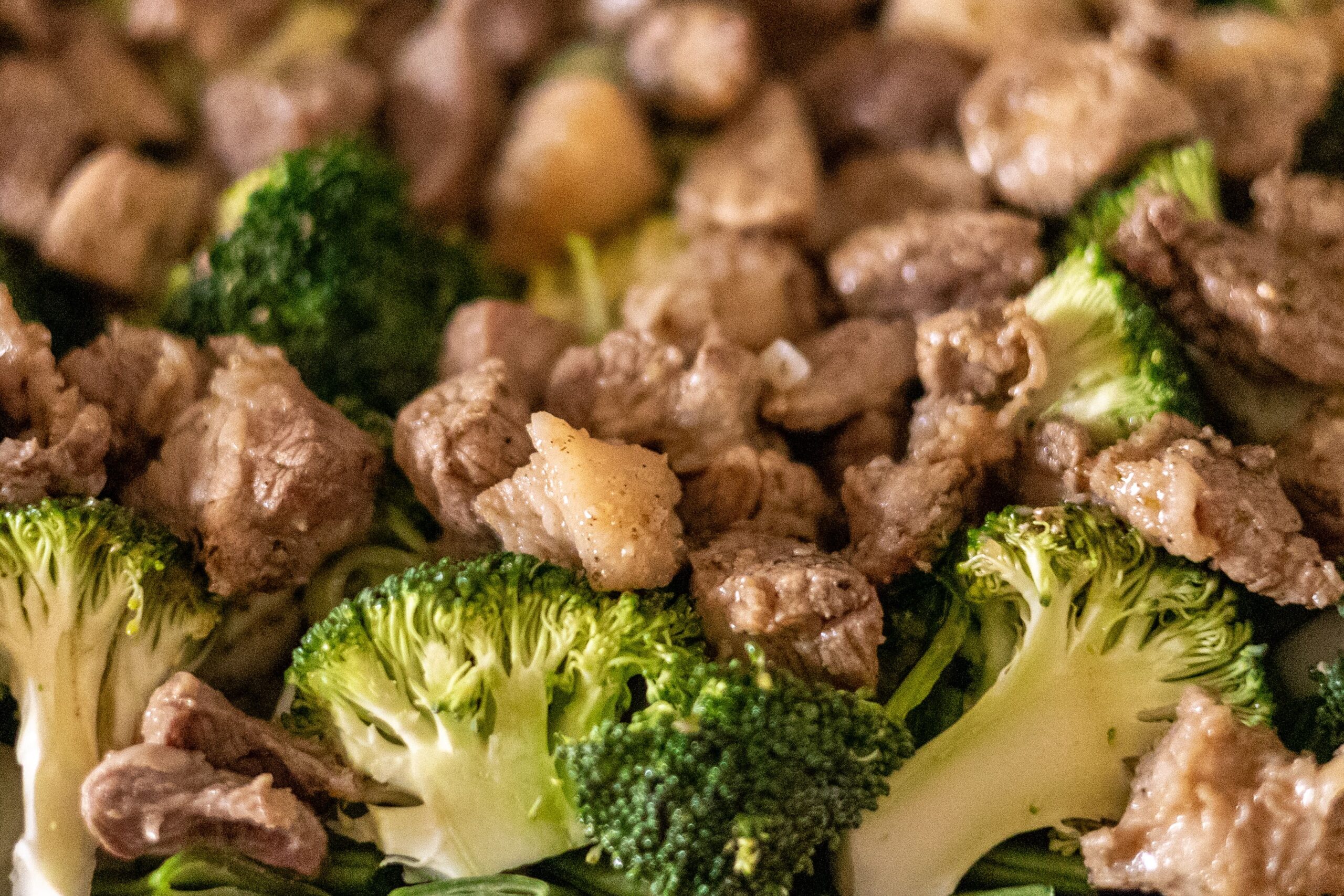Close up of tender beef pieces searing with fresh broccoli florets