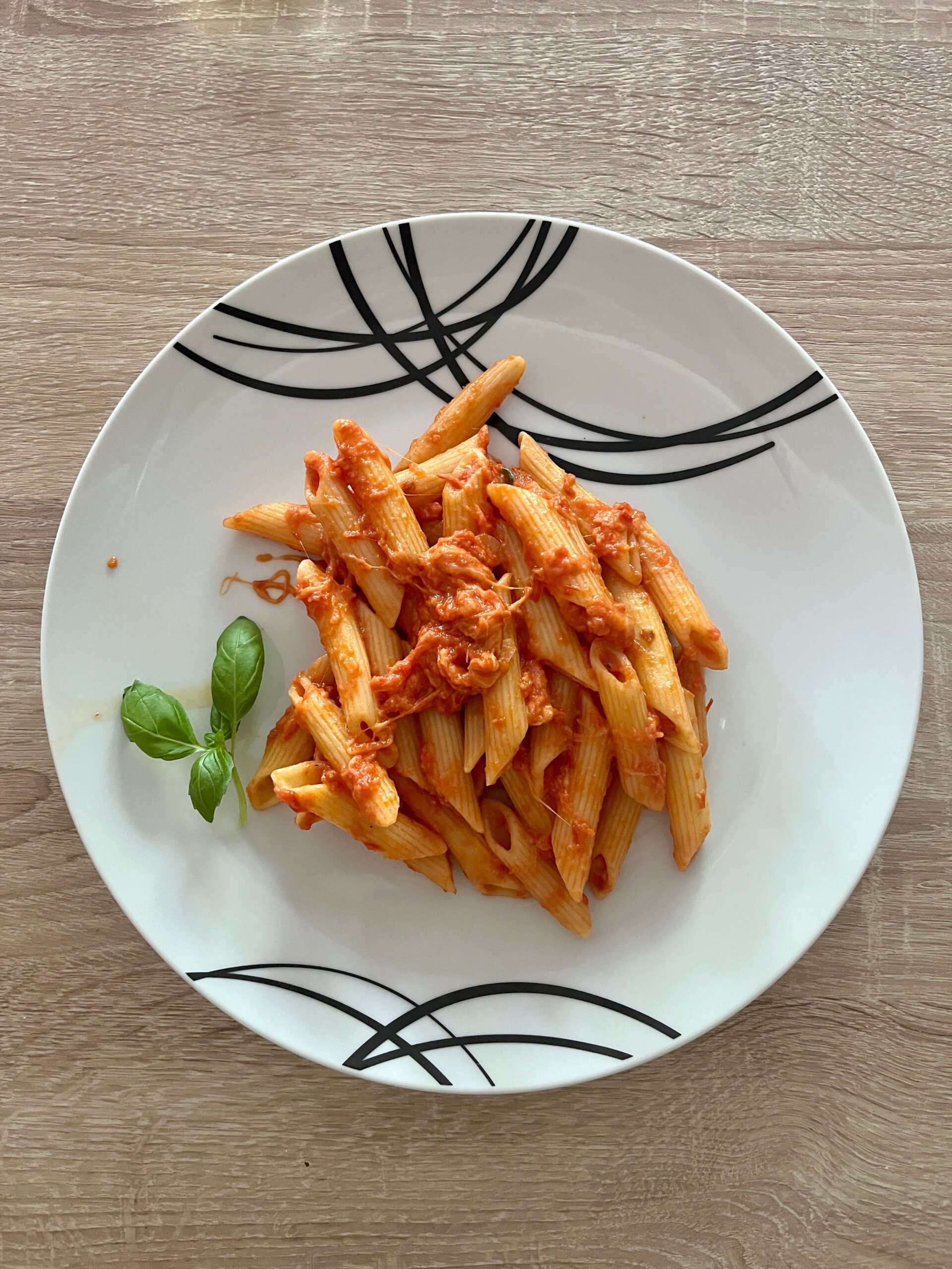 Al dente penne pasta coated in rich crushed cherry tomato sauce garnished with fresh basil leaves and halved tomatoes