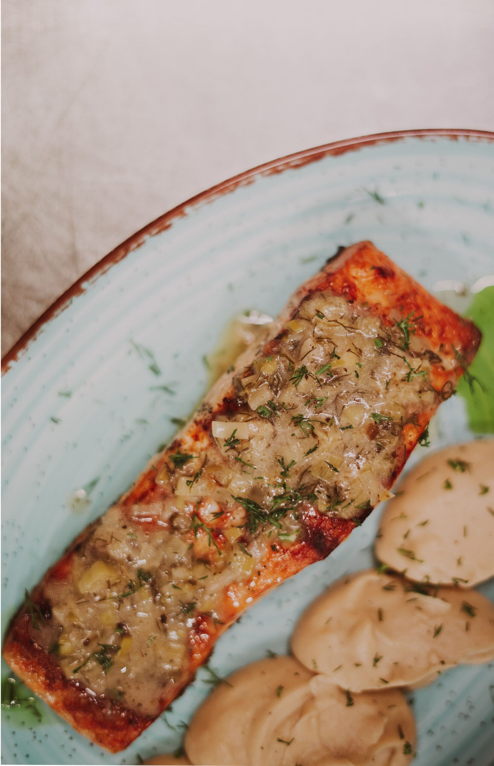 Herb-crusted roasted salmon fillet plated with delicate cream sauce and greens