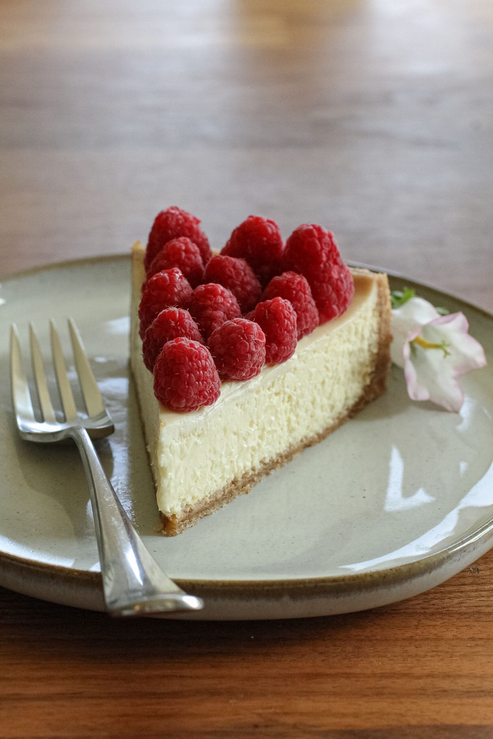 Classic slice of dense and creamy New York cheesecake served on a white dessert plate
