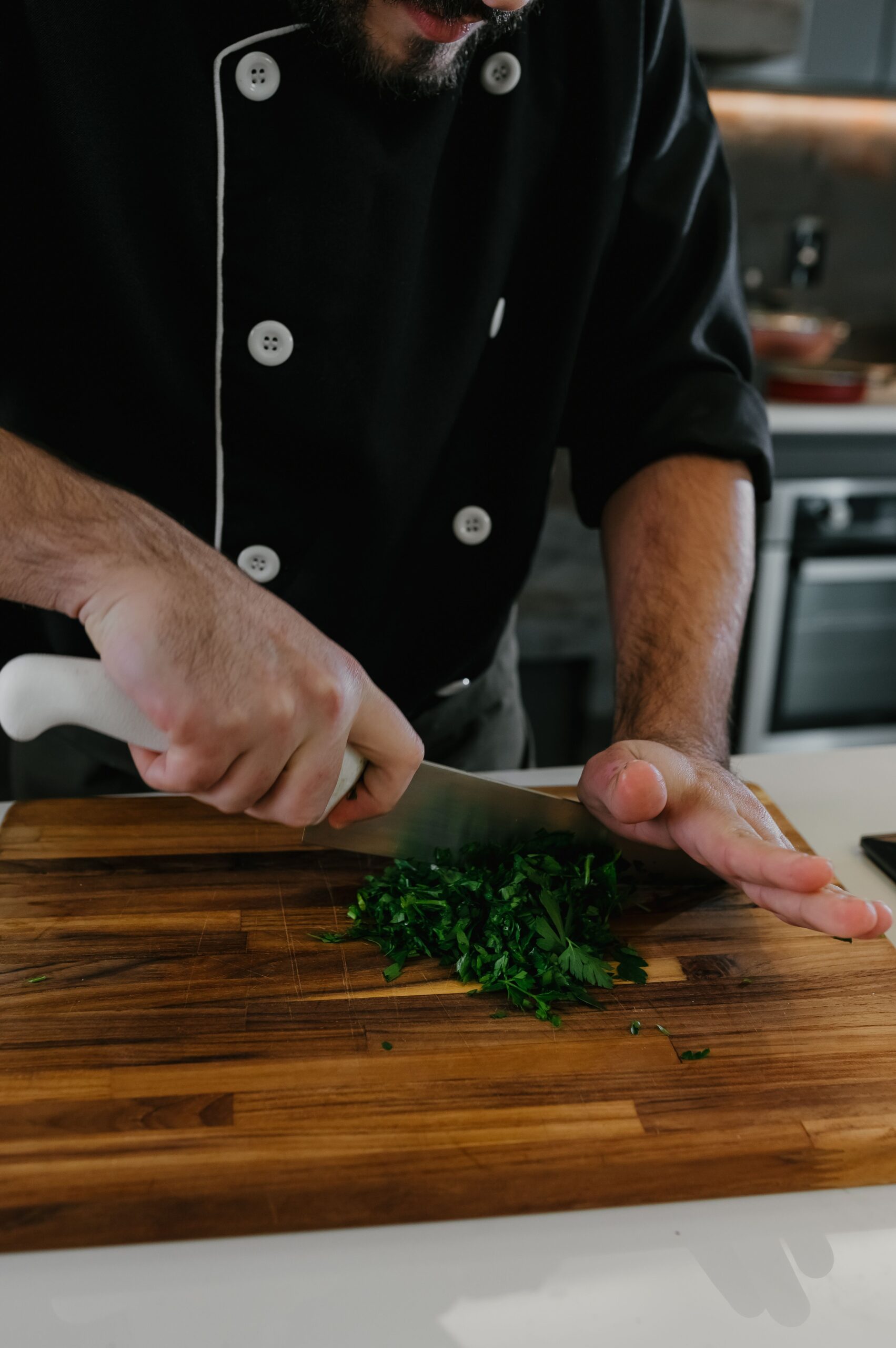 Professional chef mincing fresh flat-leaf parsley using the two-handed rock chop method