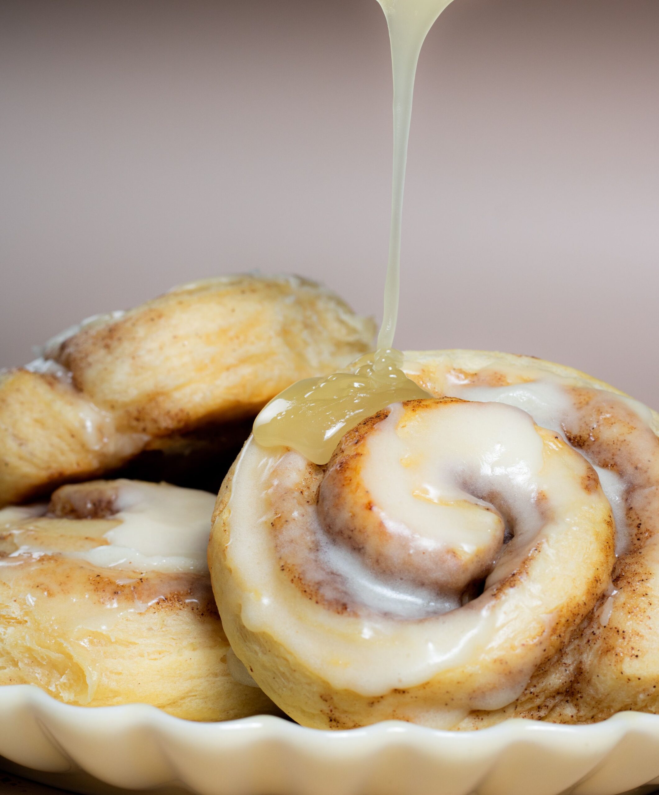 Freshly baked golden cinnamon rolls topped with thick melting cream cheese frosting