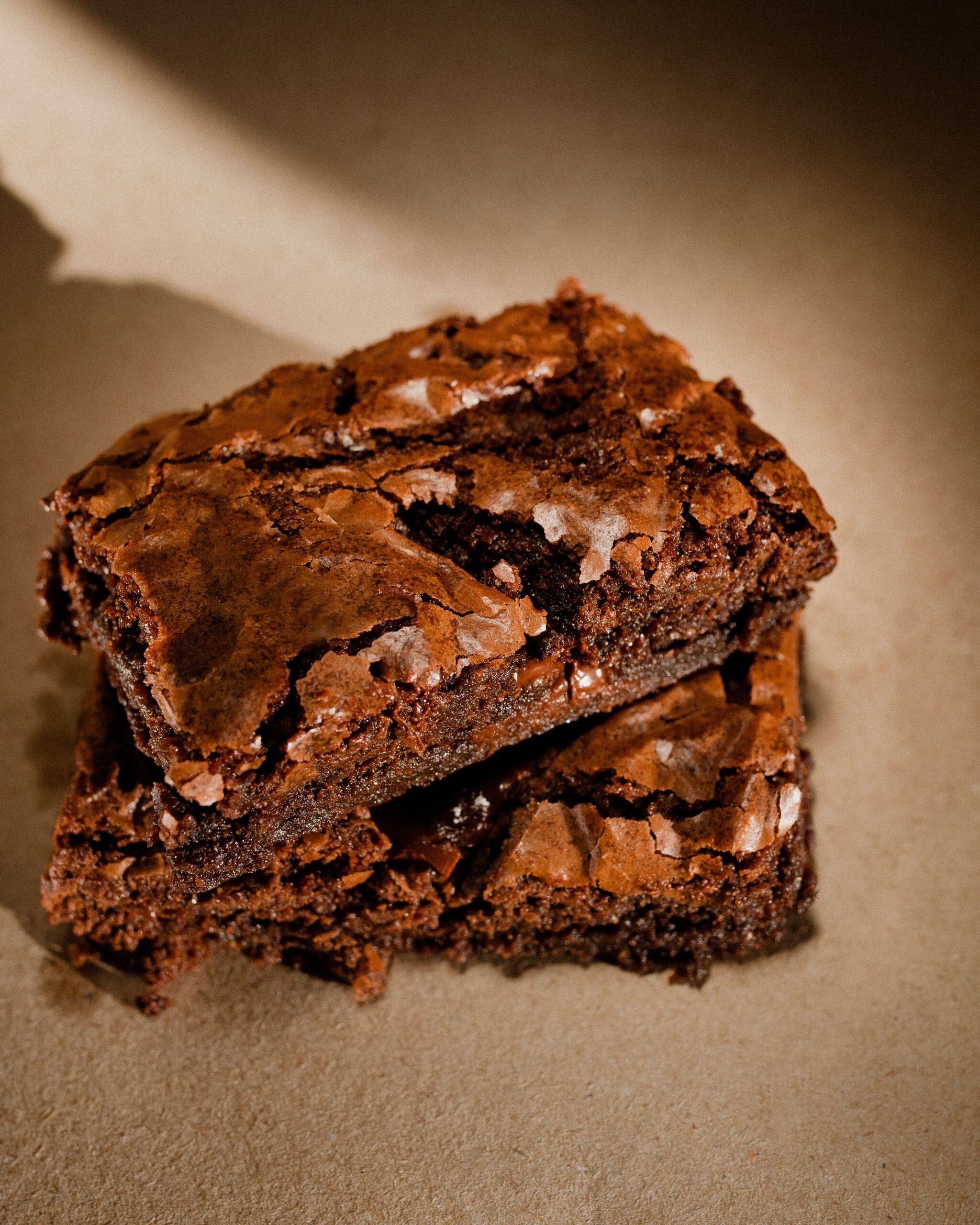 Slicing cooled fudgy chocolate brownies on a wooden cutting board with a chef knife