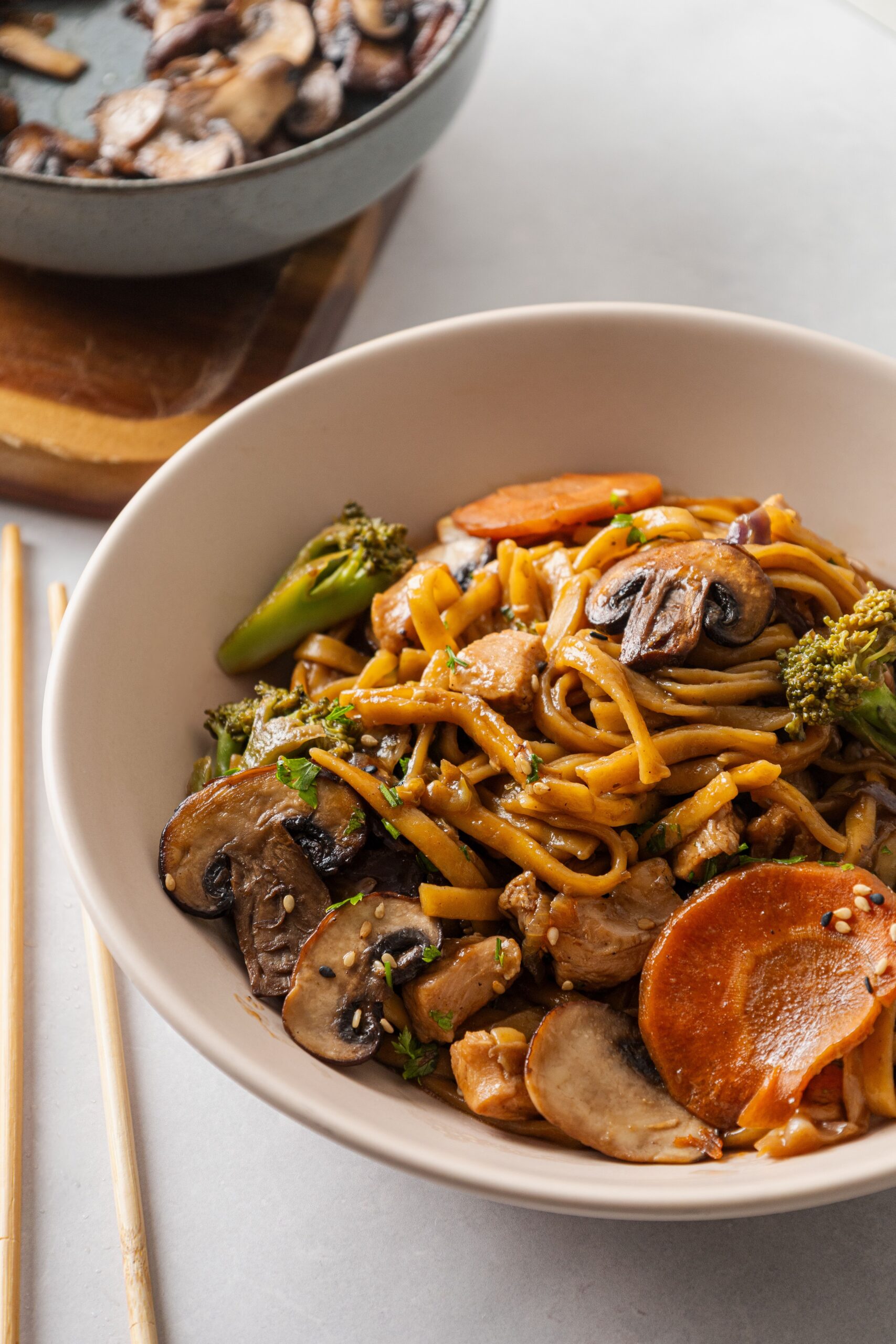 Bowl of stir-fried noodles tossed with sautéed mushrooms carrots and crisp broccoli