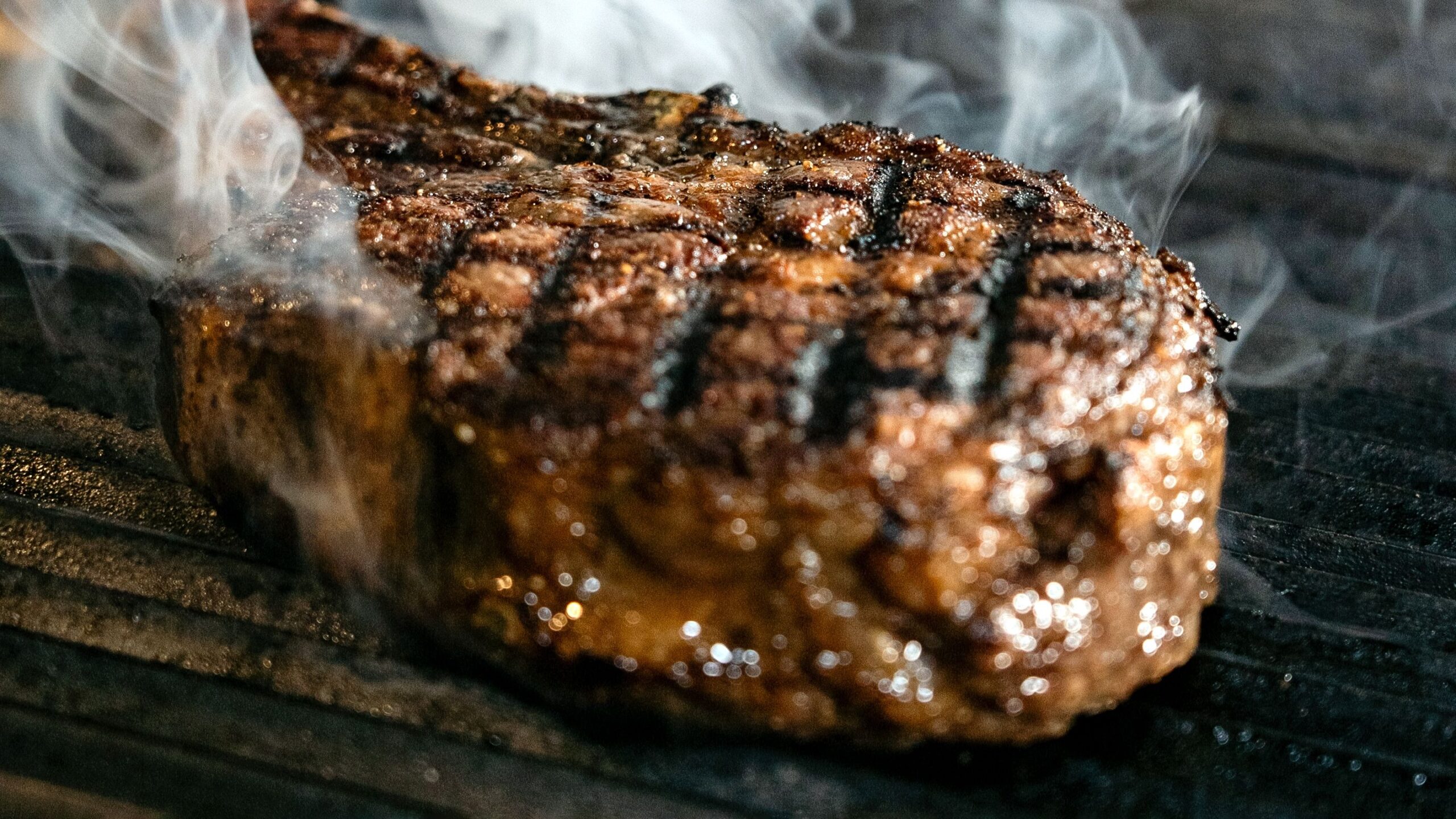Grilled bone-in tomahawk ribeye steak resting on a wooden carving board