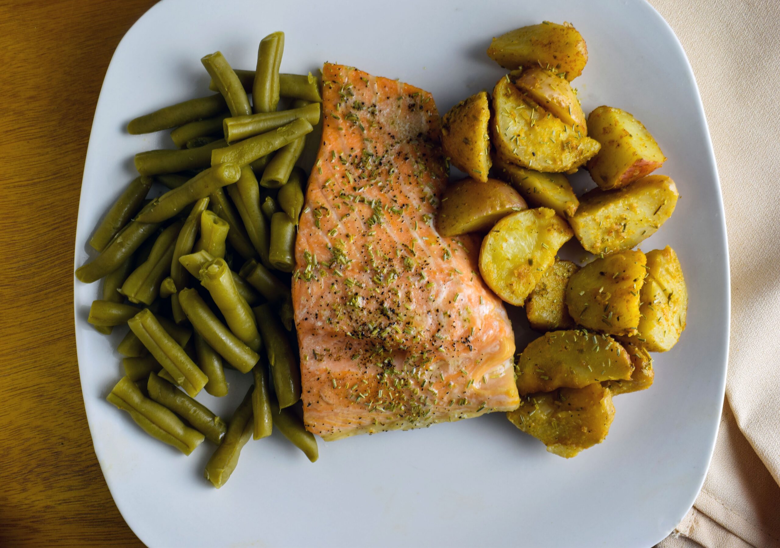 Grilled salmon steak served with boiled potatoes and fresh salad greens on a plate