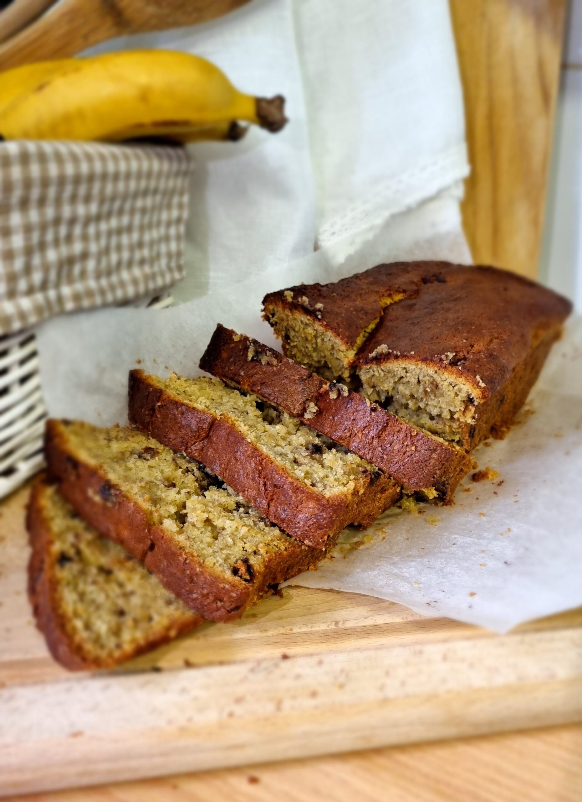 Thick slices of golden moist banana bread resting on a rustic wooden board